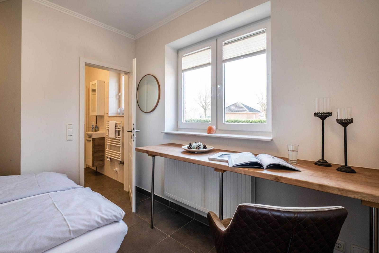 Schlafzimmer mit Schreibtisch, Bett und Blick auf die Straße.