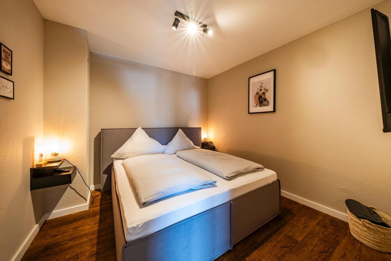 Schlafzimmer mit Doppelbett, Wandlampen und Holzboden.