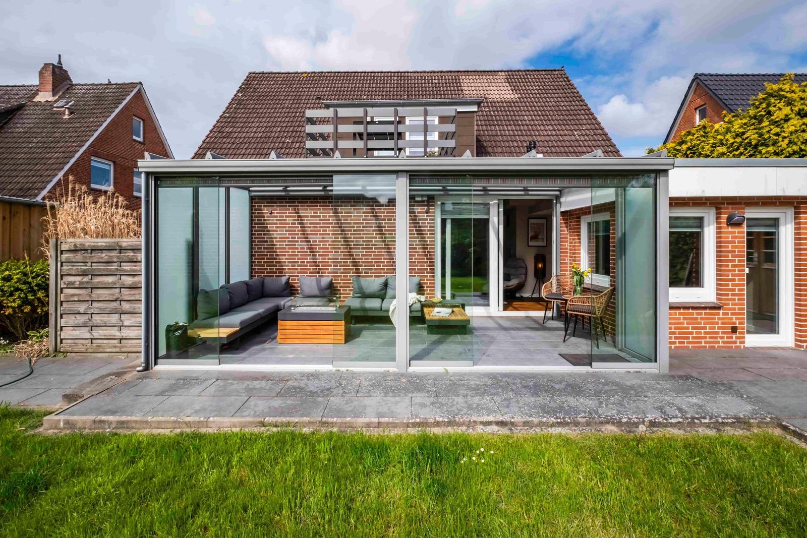 Glasveranda mit Sitzgelegenheiten und Blick auf den Garten
