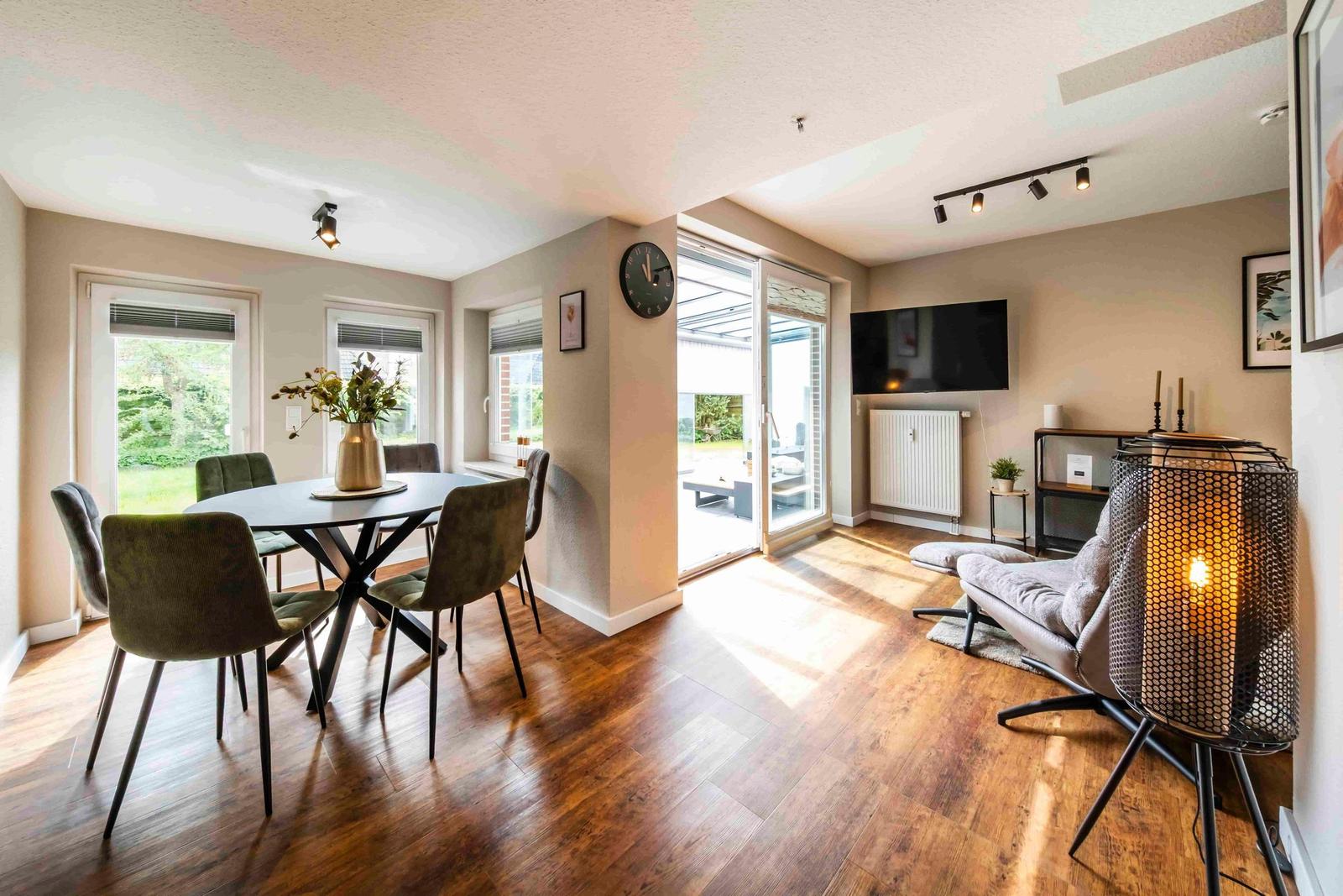 Esszimmer mit Tisch und Stühlen. Wohnbereich mit Sofa, Fernseher und Bodenheizung.