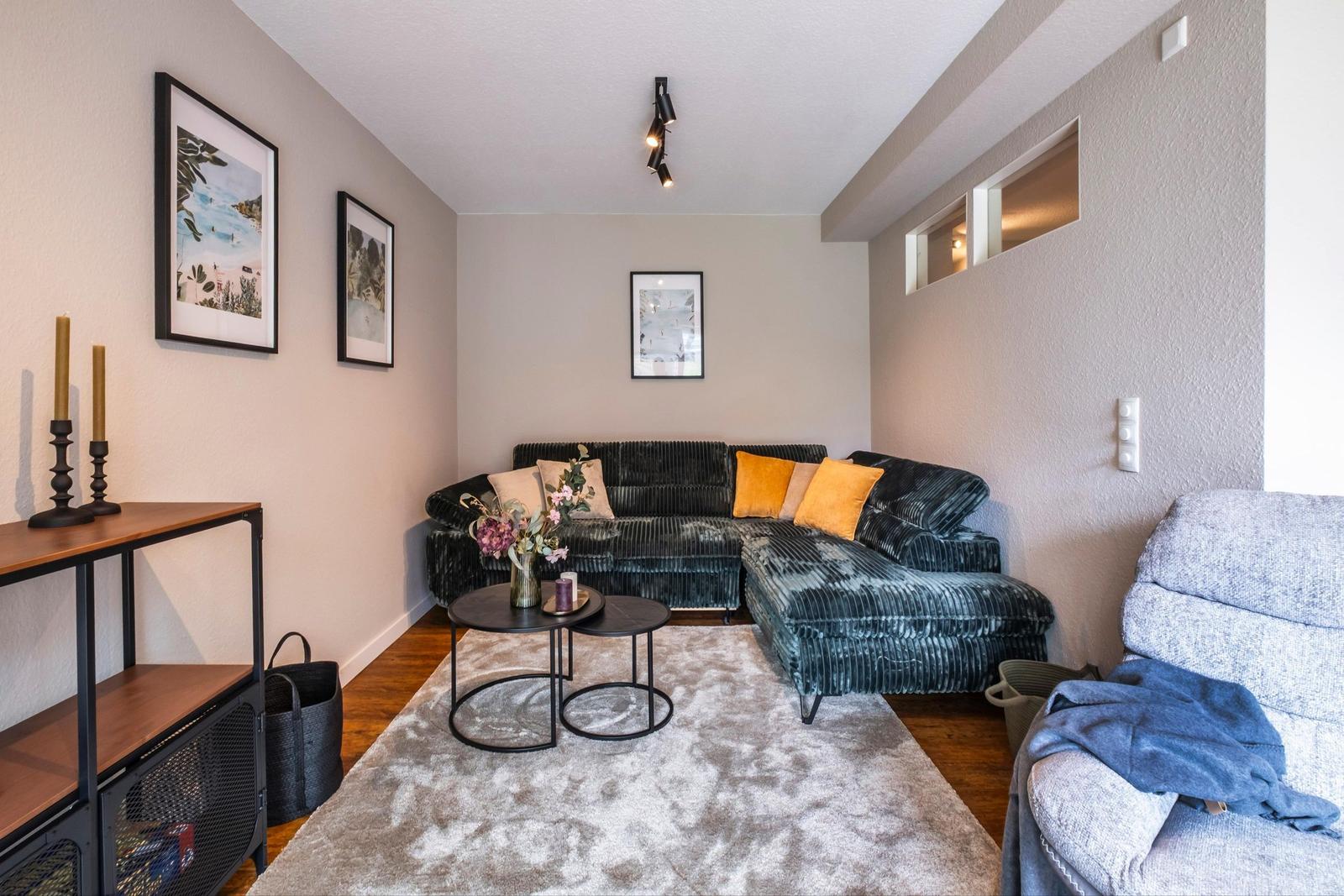 Wohnzimmer mit Ecksofa, Teppich und Bildern an den Wänden.
