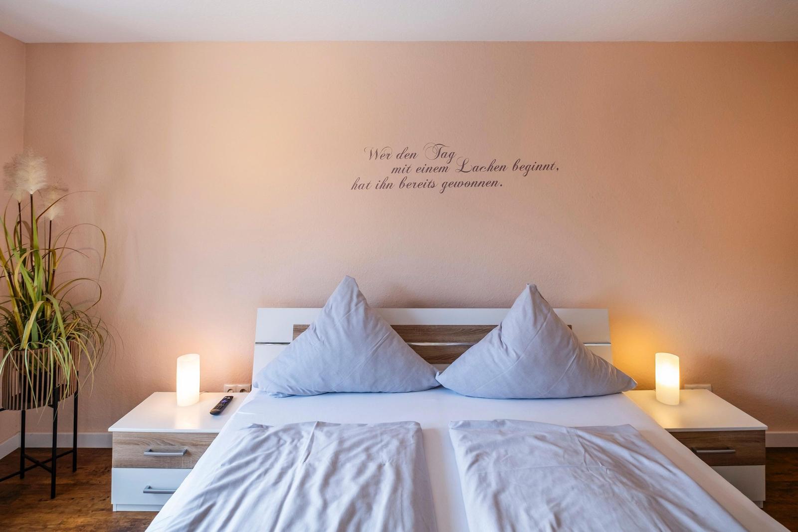 Schlafzimmer mit Bett, Nachttischen und Wanddekoration.