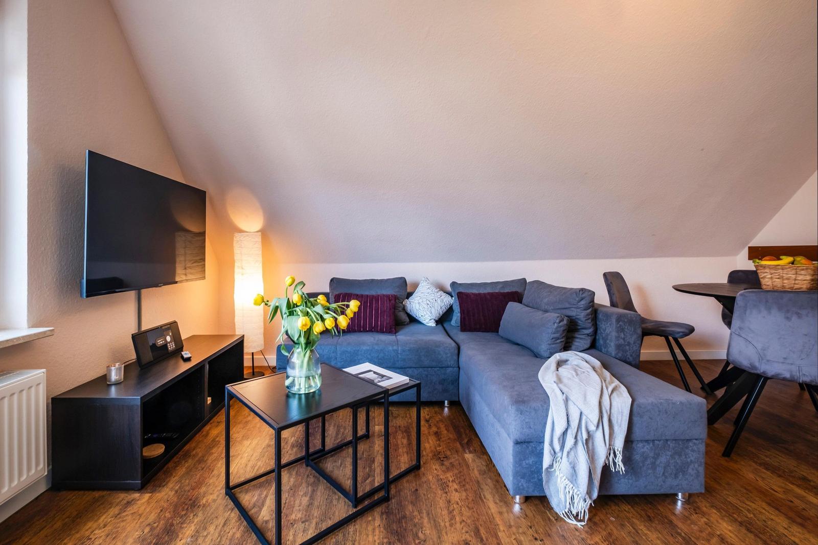Wohnbereich mit Sofa, Fernseher und Esstisch