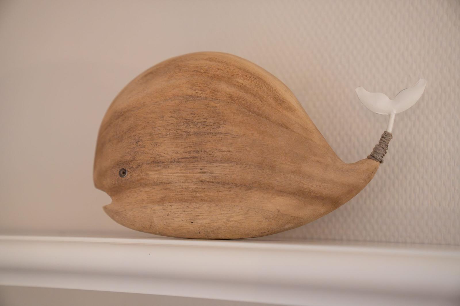 Holzfigur eines Walles mit weißem Flosselement auf weißer Oberfläche