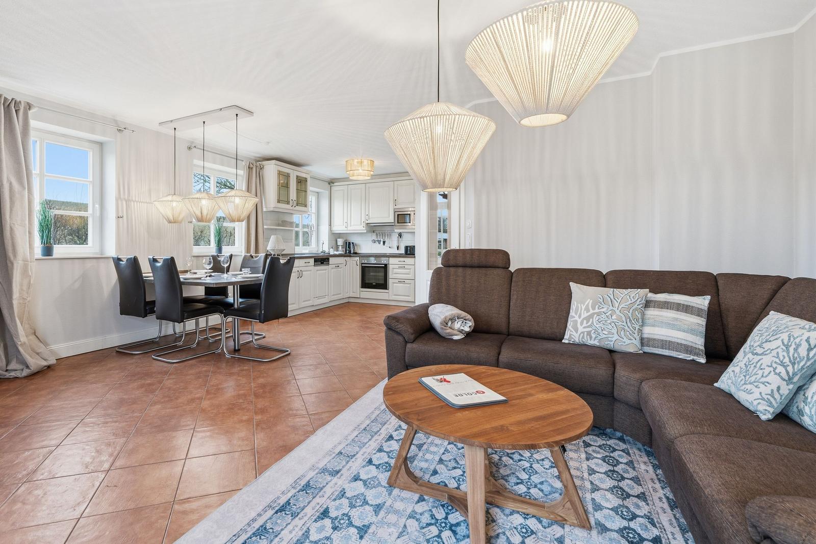 Wohn- und Essbereich mit braunem Sofa, Holztisch und Küchenbereich.