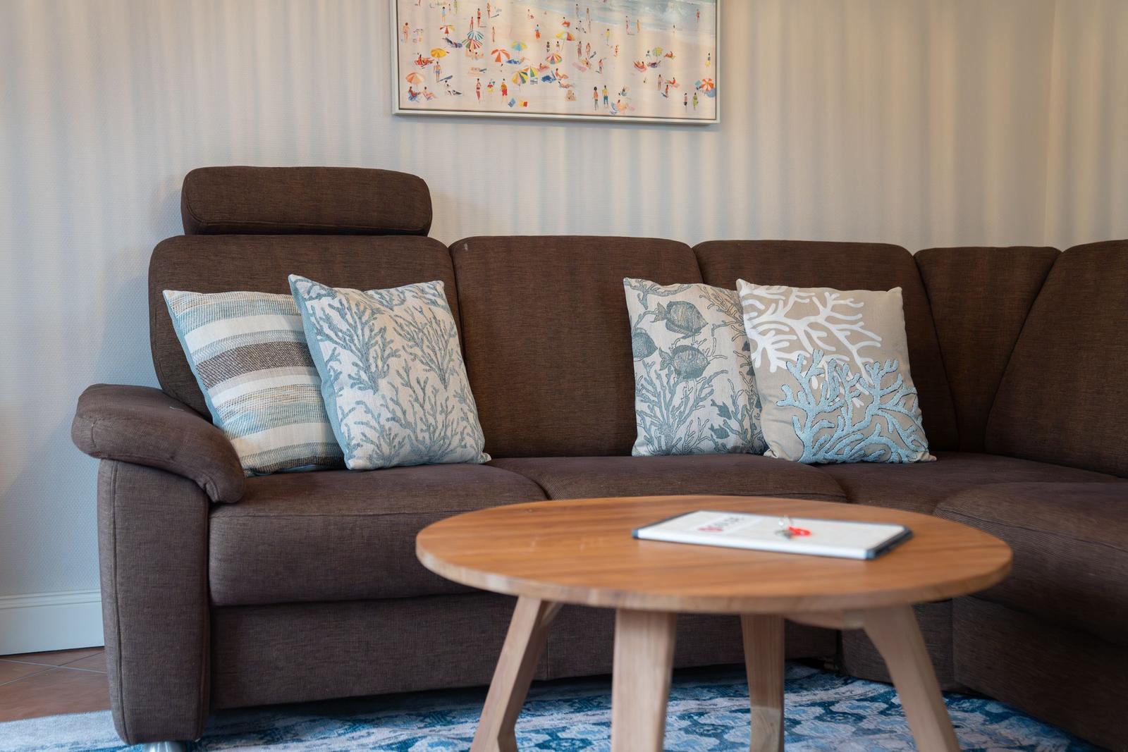 Ein brauner Sofa mit Kissen und einem runden Tisch vor einem Wandbild.