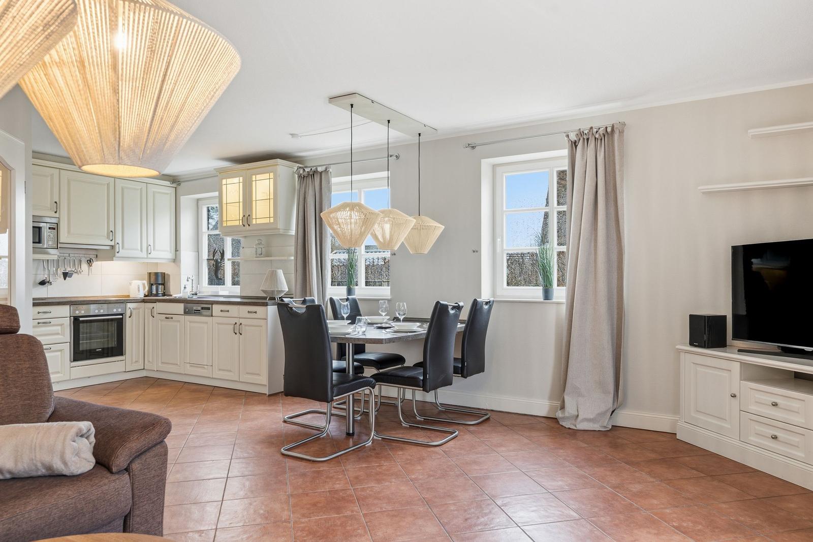 Küche mit Essbereich und Wohnbereich mit TV und Sofa.