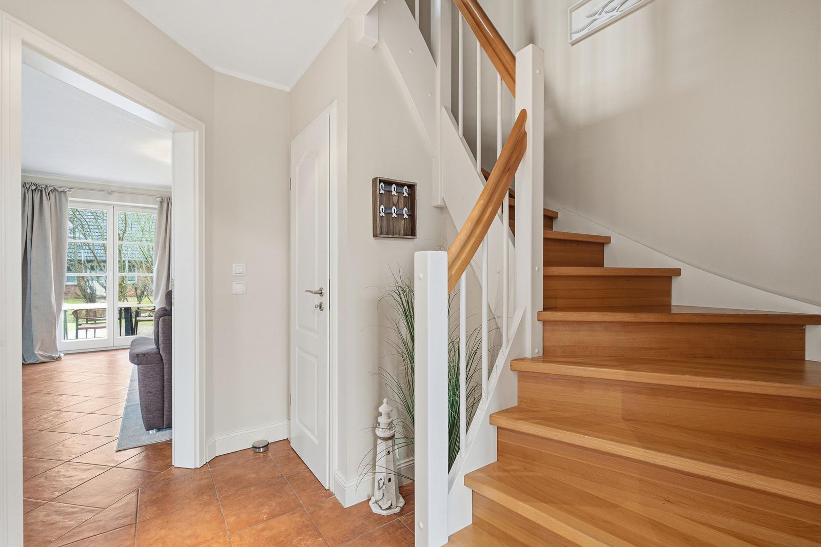 Haus mit Holztreppe und Terrasse. Blick in Wohnzimmer mit Sofa und Fenster.