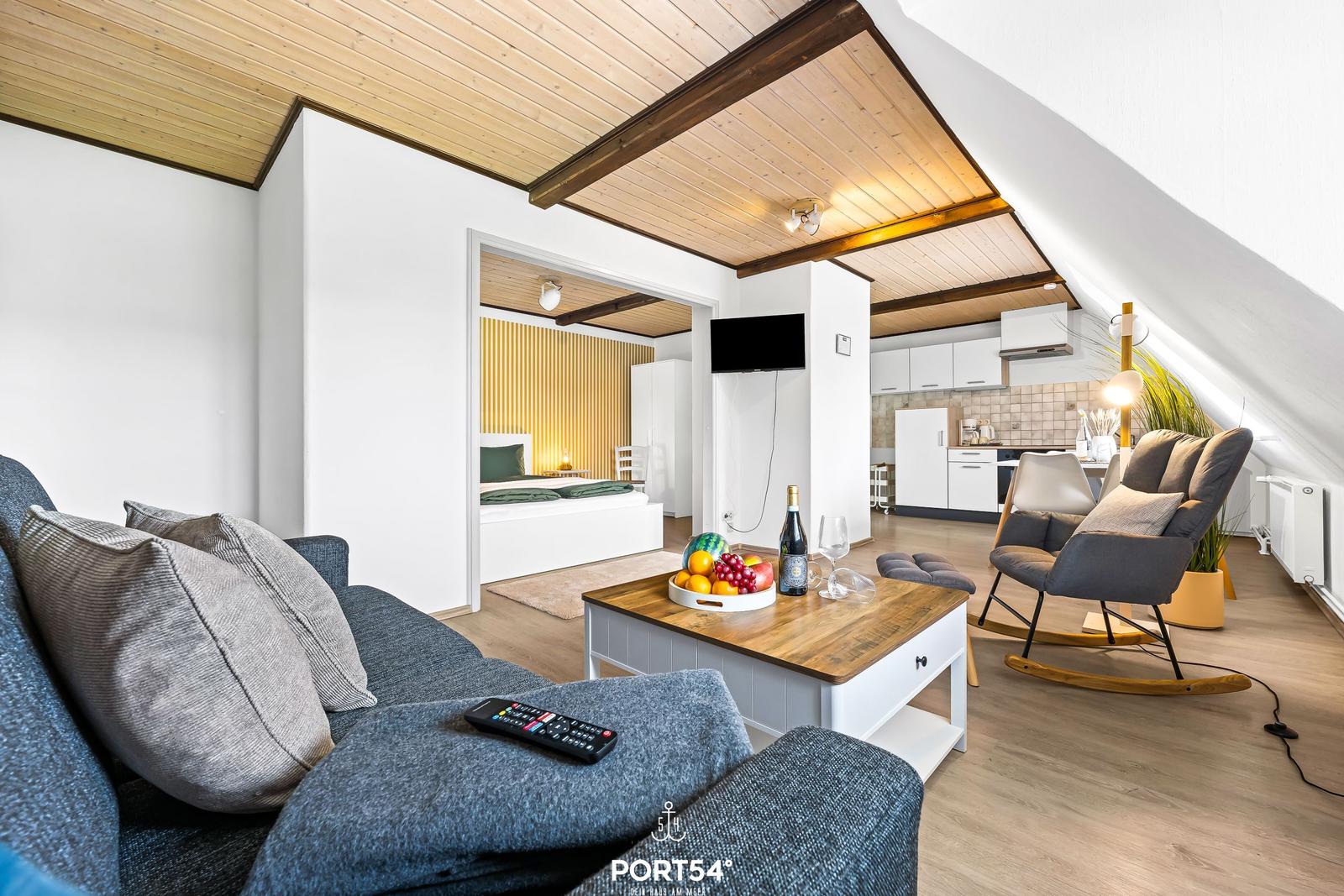 Wohnbereich mit Sofa, Fernseher und Blick in Schlaf- und Küchenbereich.