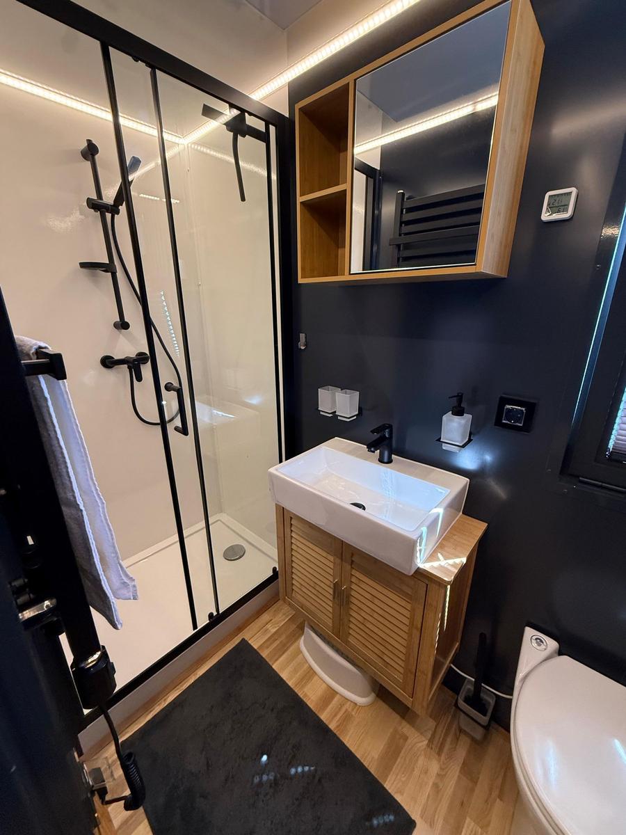 Bathroom with shower, sink, and toilet. Wooden and metal accents.