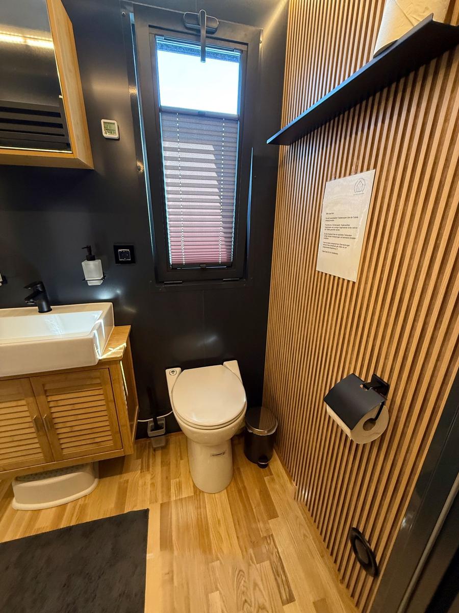 Bathroom with toilet, sink, and window with blinds.