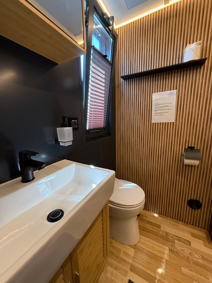 Bathroom with sink, toilet, and wooden wall cladding.