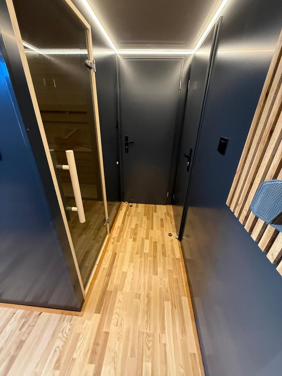 Hallway with wooden floor, dark walls, and door to sauna and bedroom