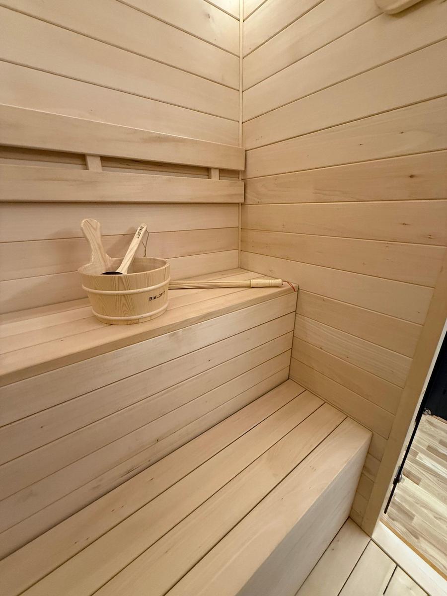 Sauna with wooden bench and bucket with brush.