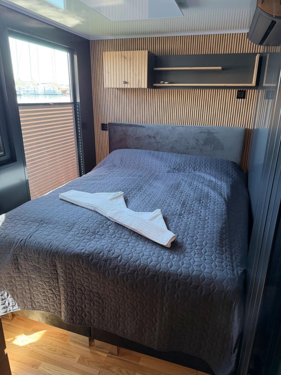 Bedroom with bed, wooden wall, and window overlooking the harbor.