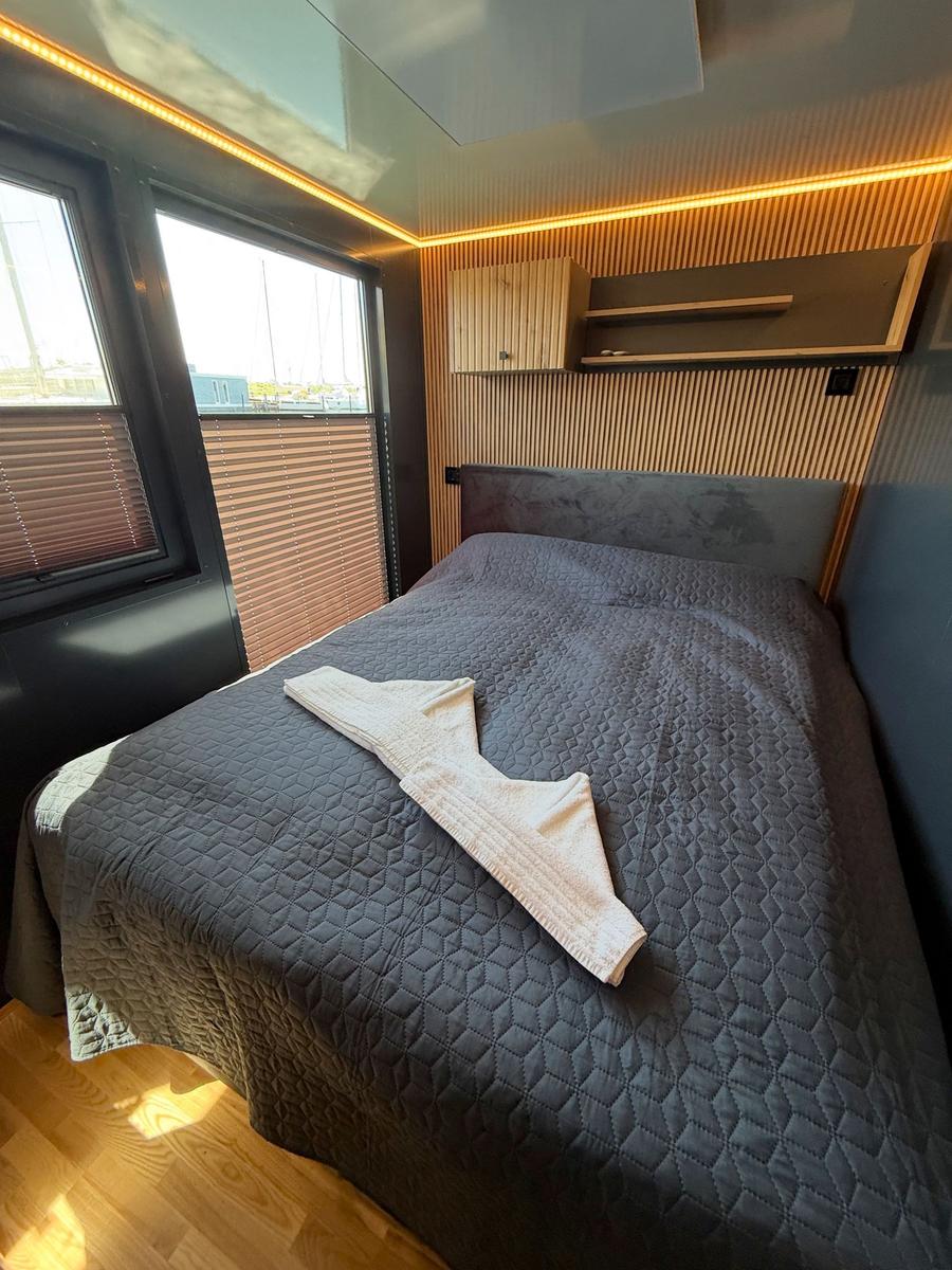 Bedroom with bed, wood paneling, and window with blinds.