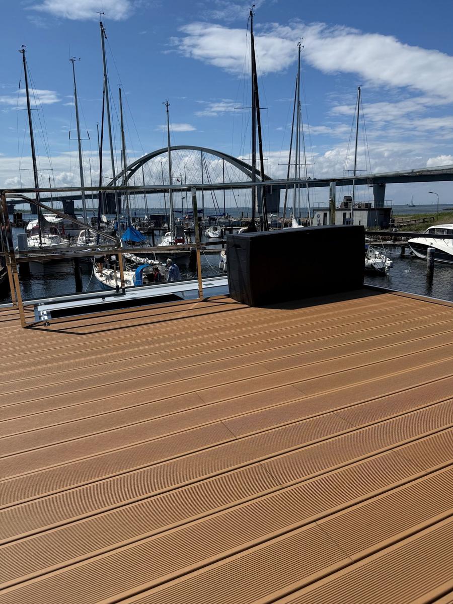 Deck with view of harbor and sailboats under blue sky.