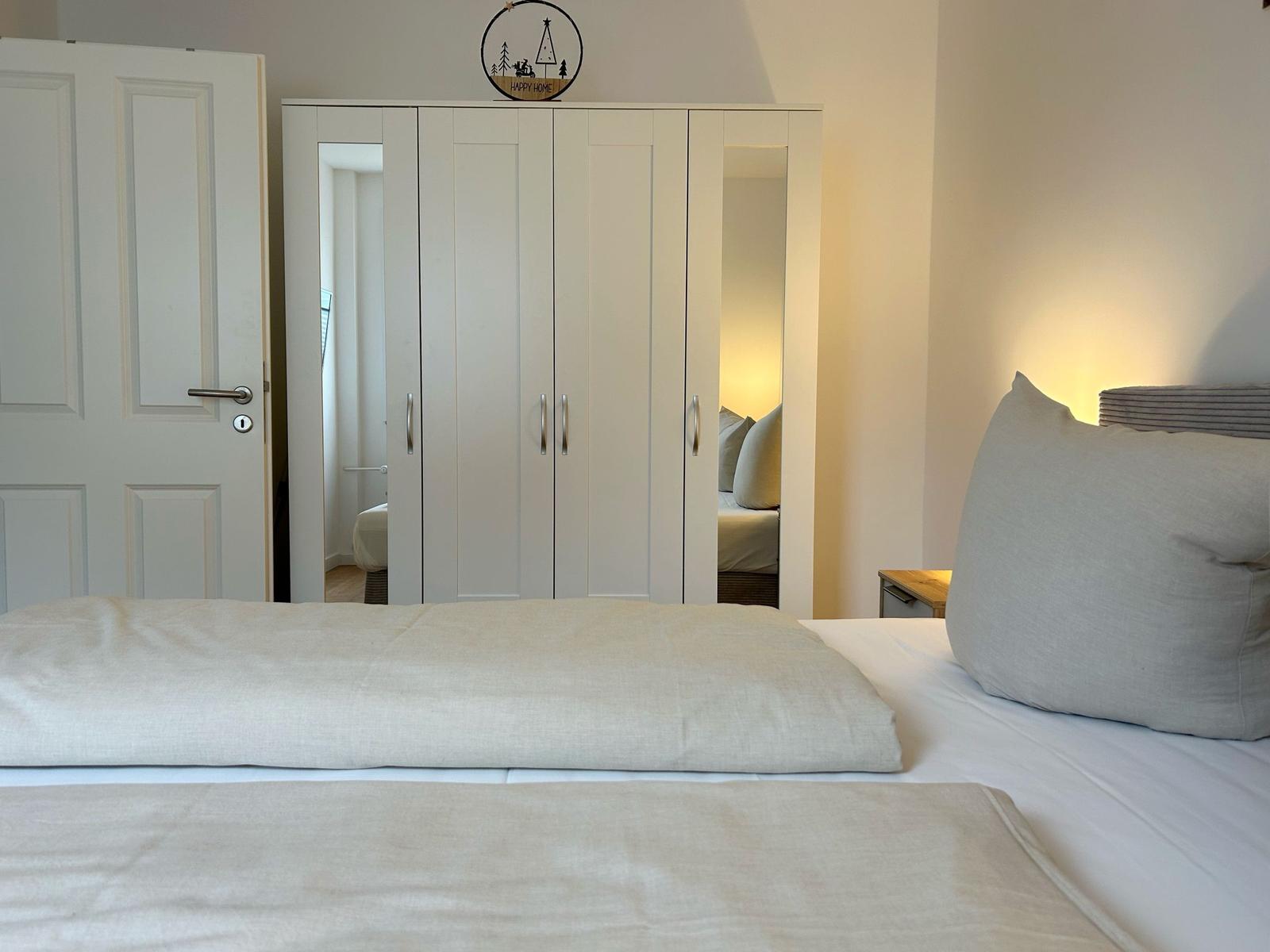Schlafzimmer mit Bett, Kleiderschrank und Tür.