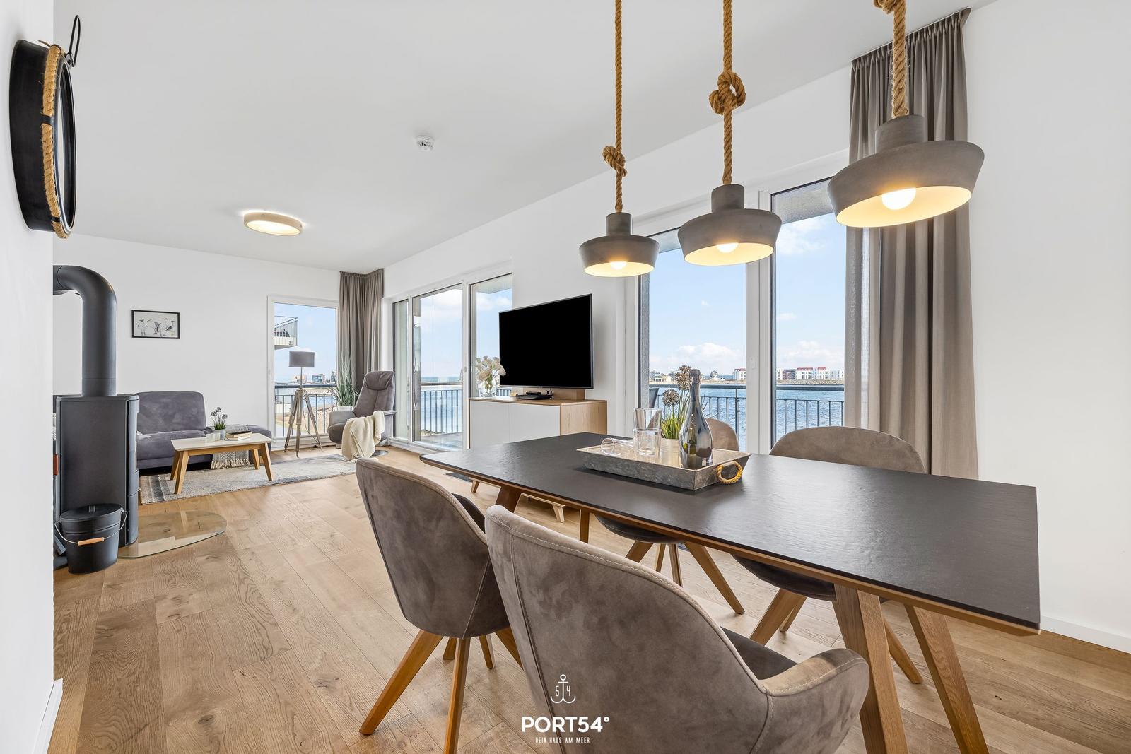 Esszimmer mit Blick aufs Wasser, Esstisch mit Stühlen und Hängelampen.