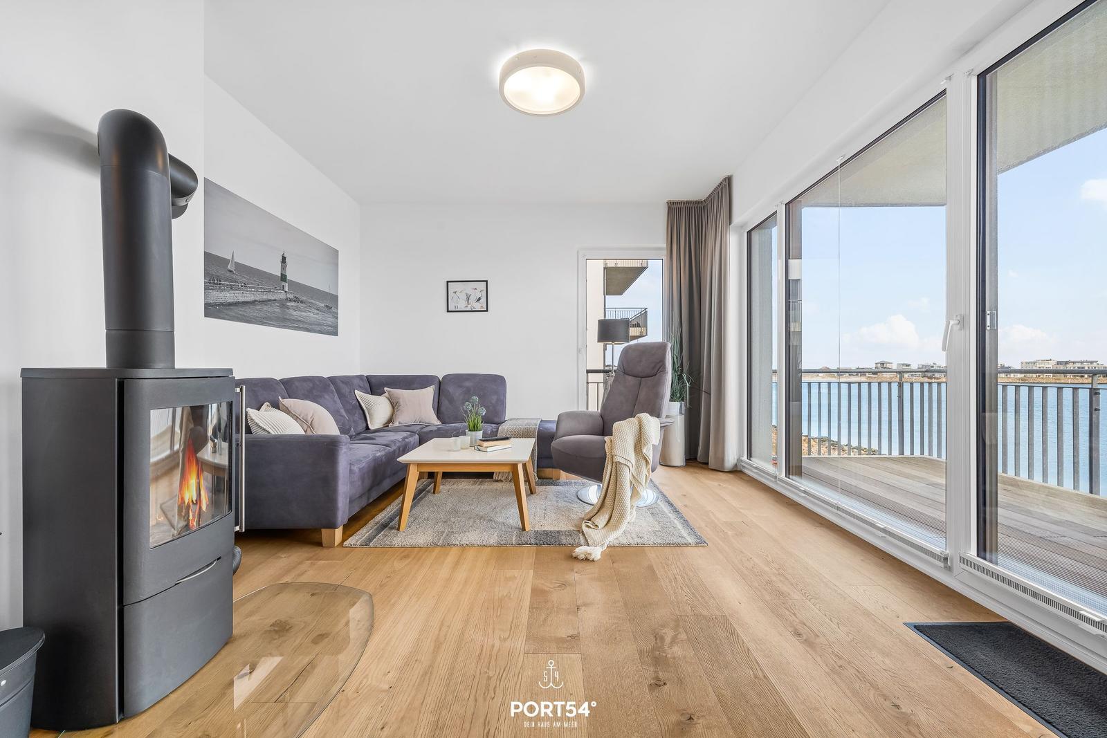 Wohnzimmer mit Kamin, Sofa und Blick auf den Hafen.