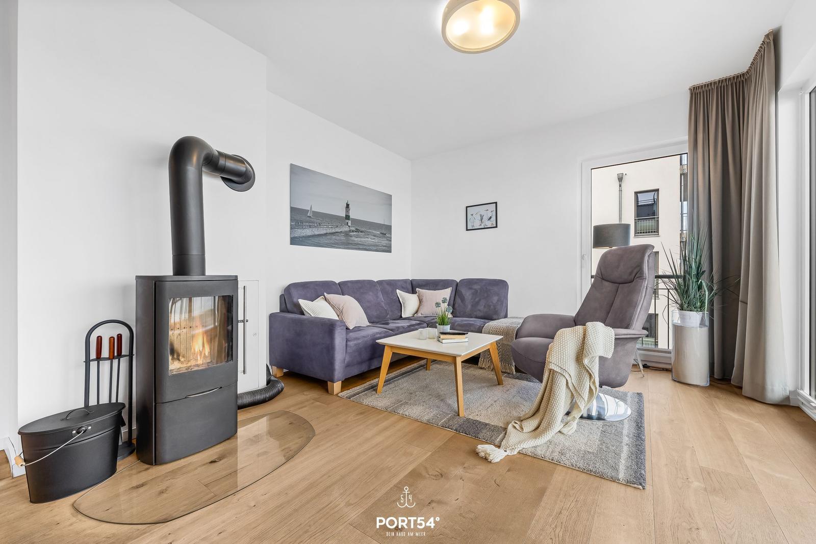 Wohnzimmer mit Sofa, Sessel, Kamin und Holzboden.