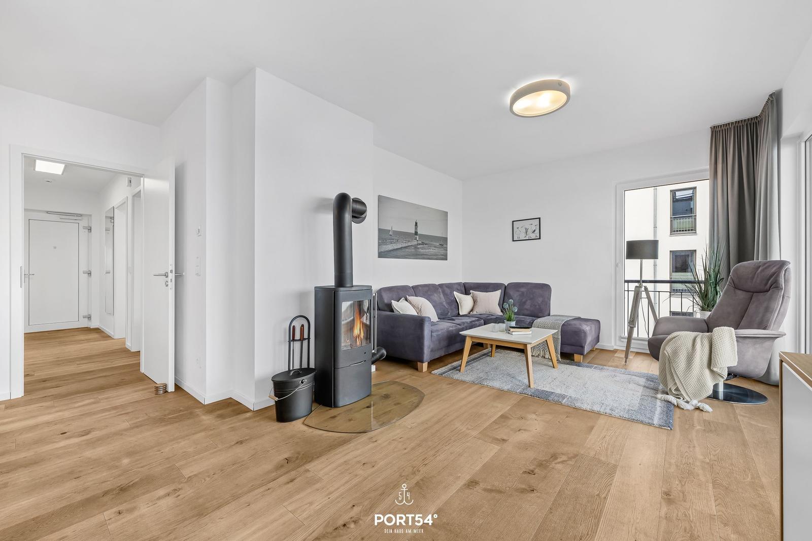 Wohnzimmer mit Sofa, Kamin und Balkonansicht.