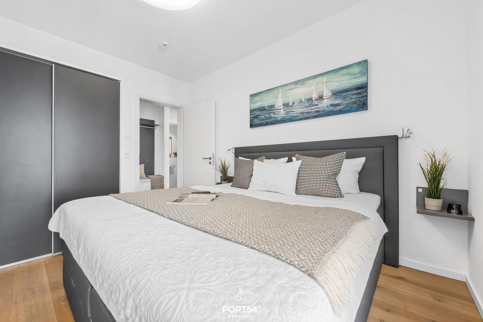 Schlafzimmer mit Doppelbett, Wandbild und Schwebemöbeln.