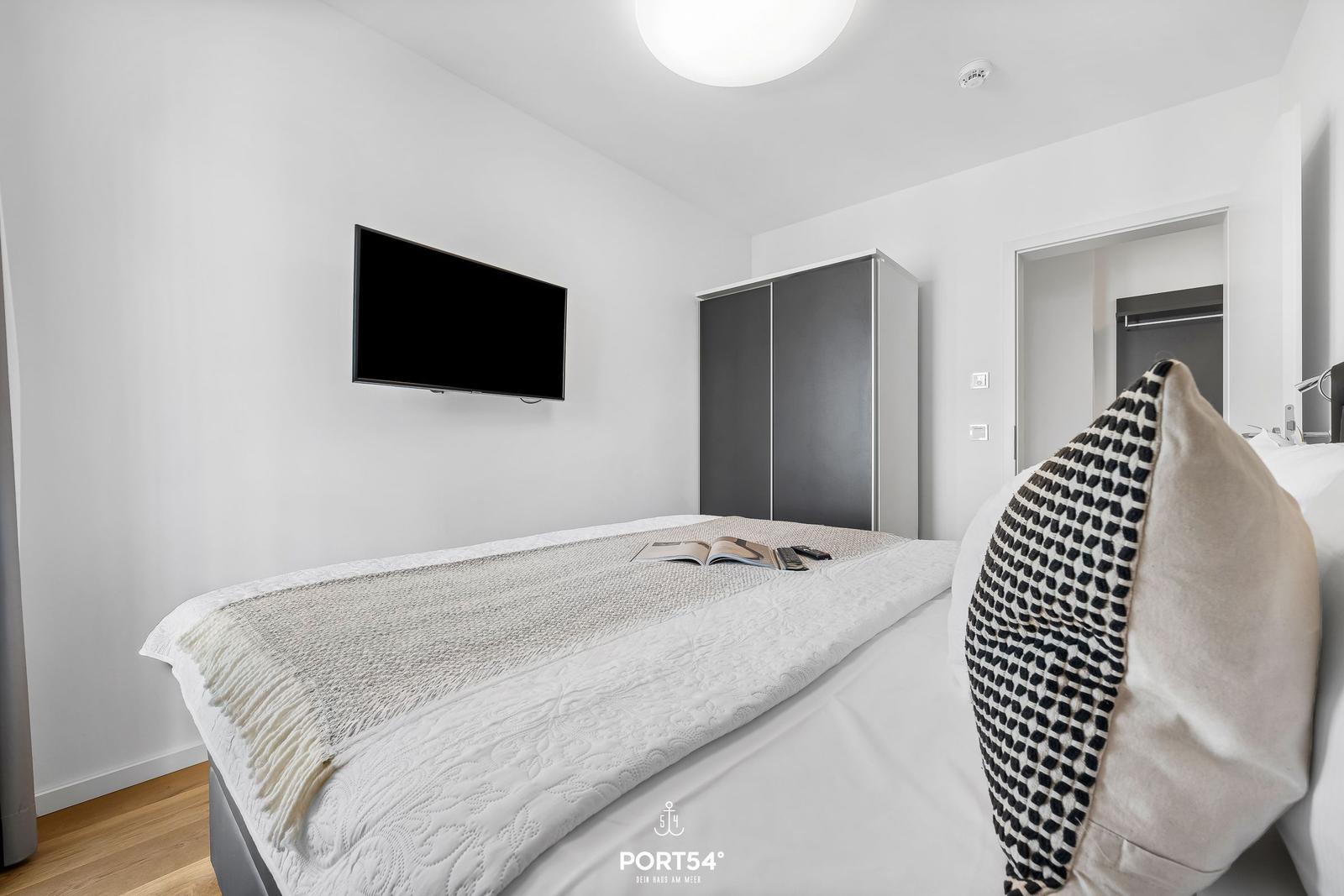 Schlafzimmer mit Bett, TV und Kleiderschrank. Moderne Einrichtung.
