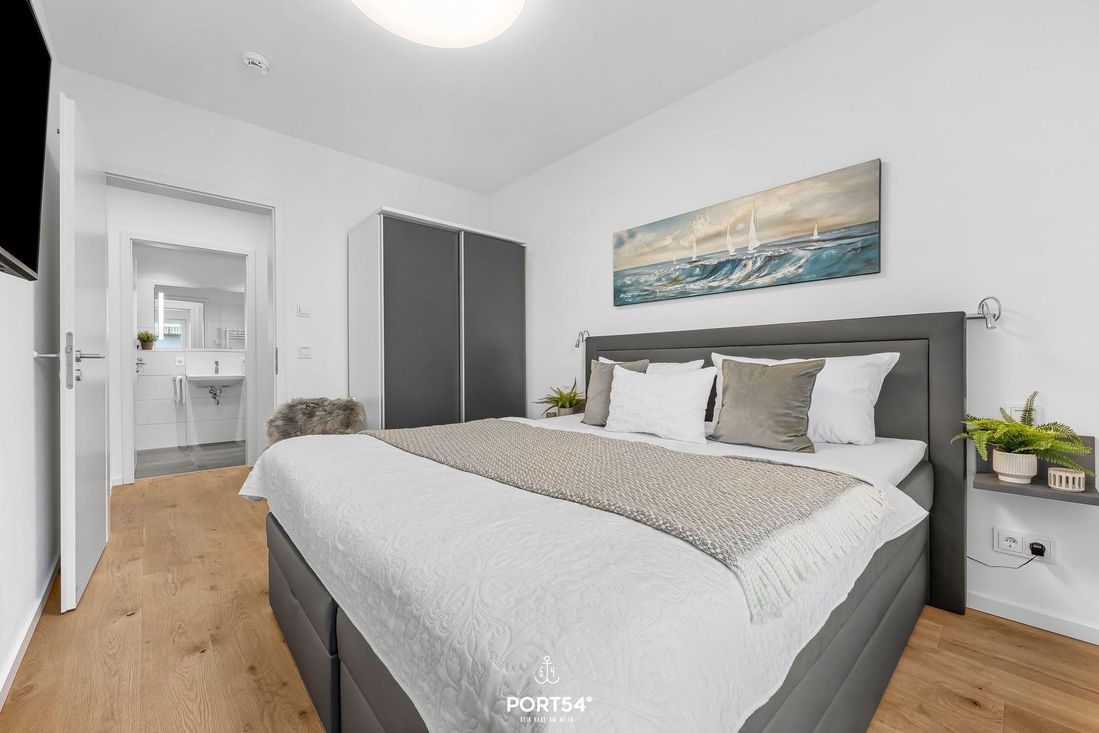 Schlafzimmer mit Bett, Wandbild und Schlafzimmer. Holzboden und graue Möbel.