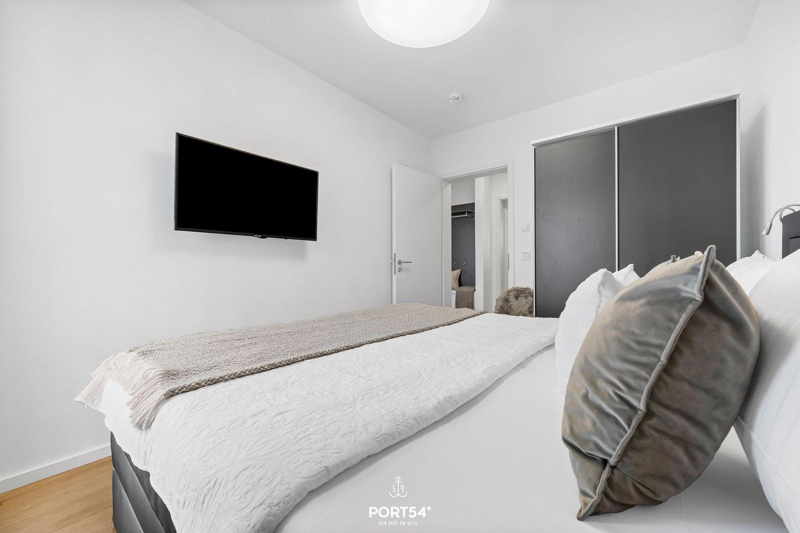 Schlafzimmer mit Bett, TV und Kleiderschrank.