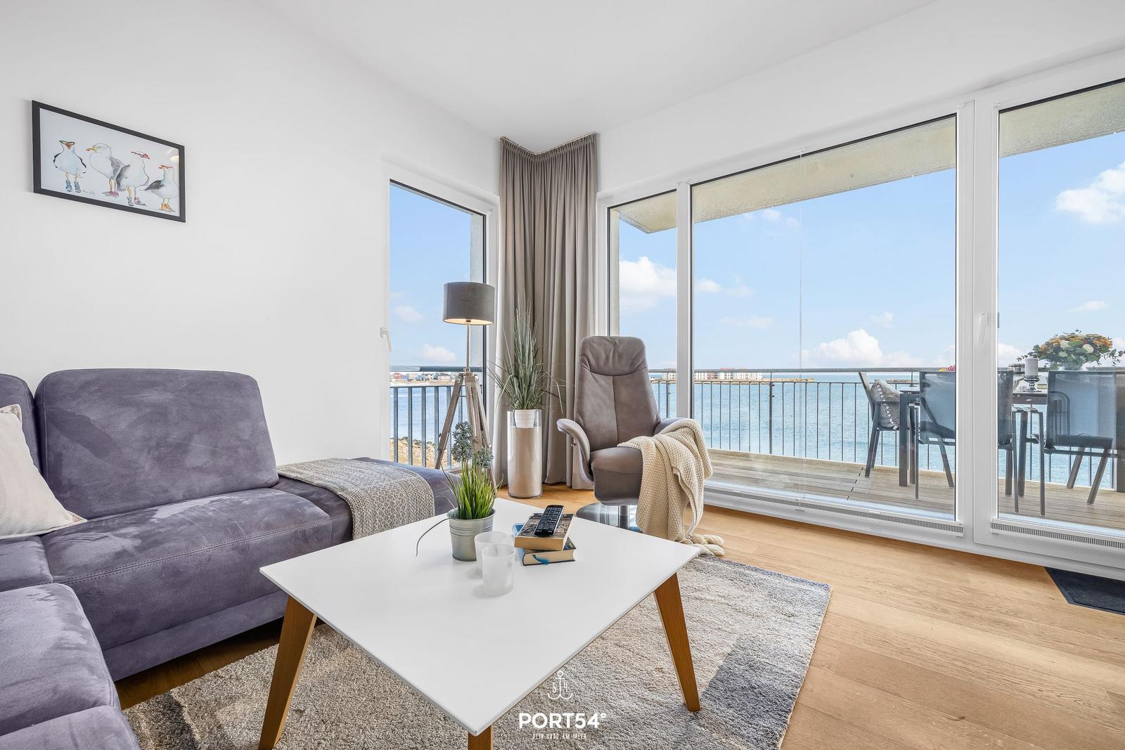 Wohnzimmer mit Sofa, Couchtisch und Meerblick über Balkon.