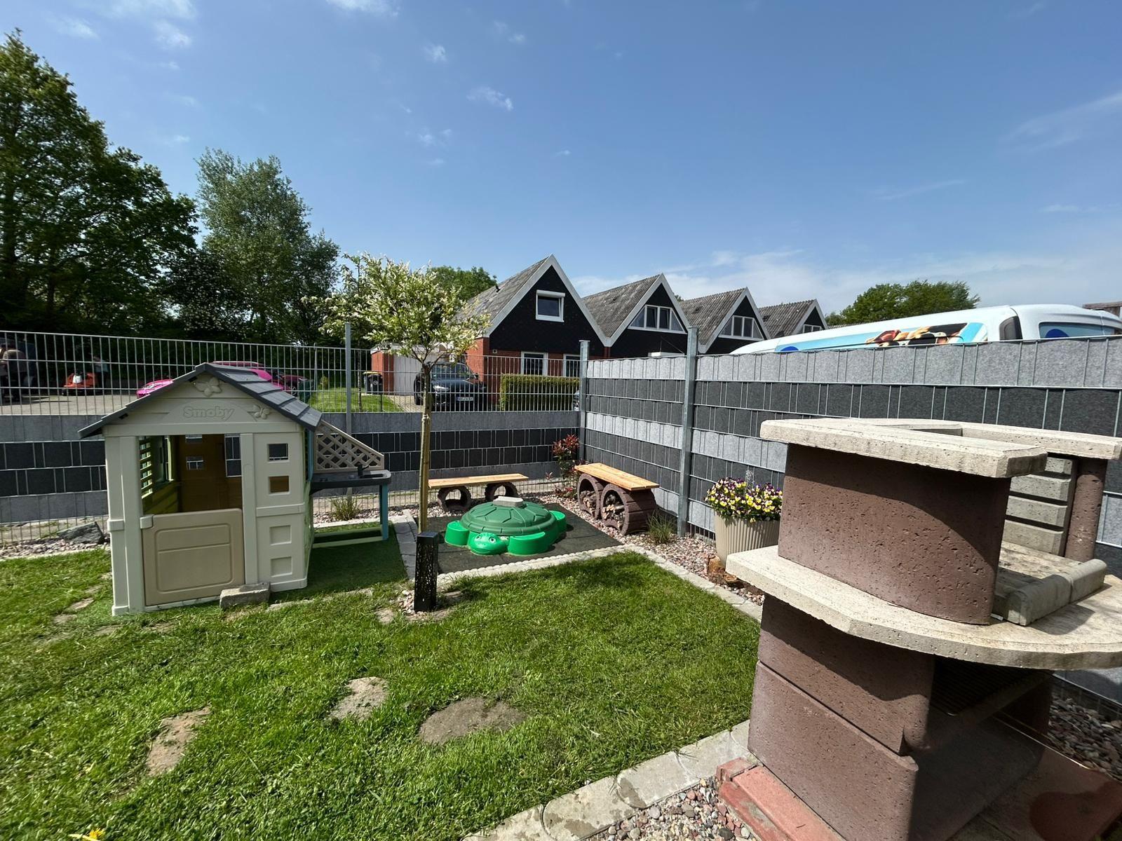 Backyard with playhouse, green seating area, and grill. Backyard with playhouse, green seating area, and grill.