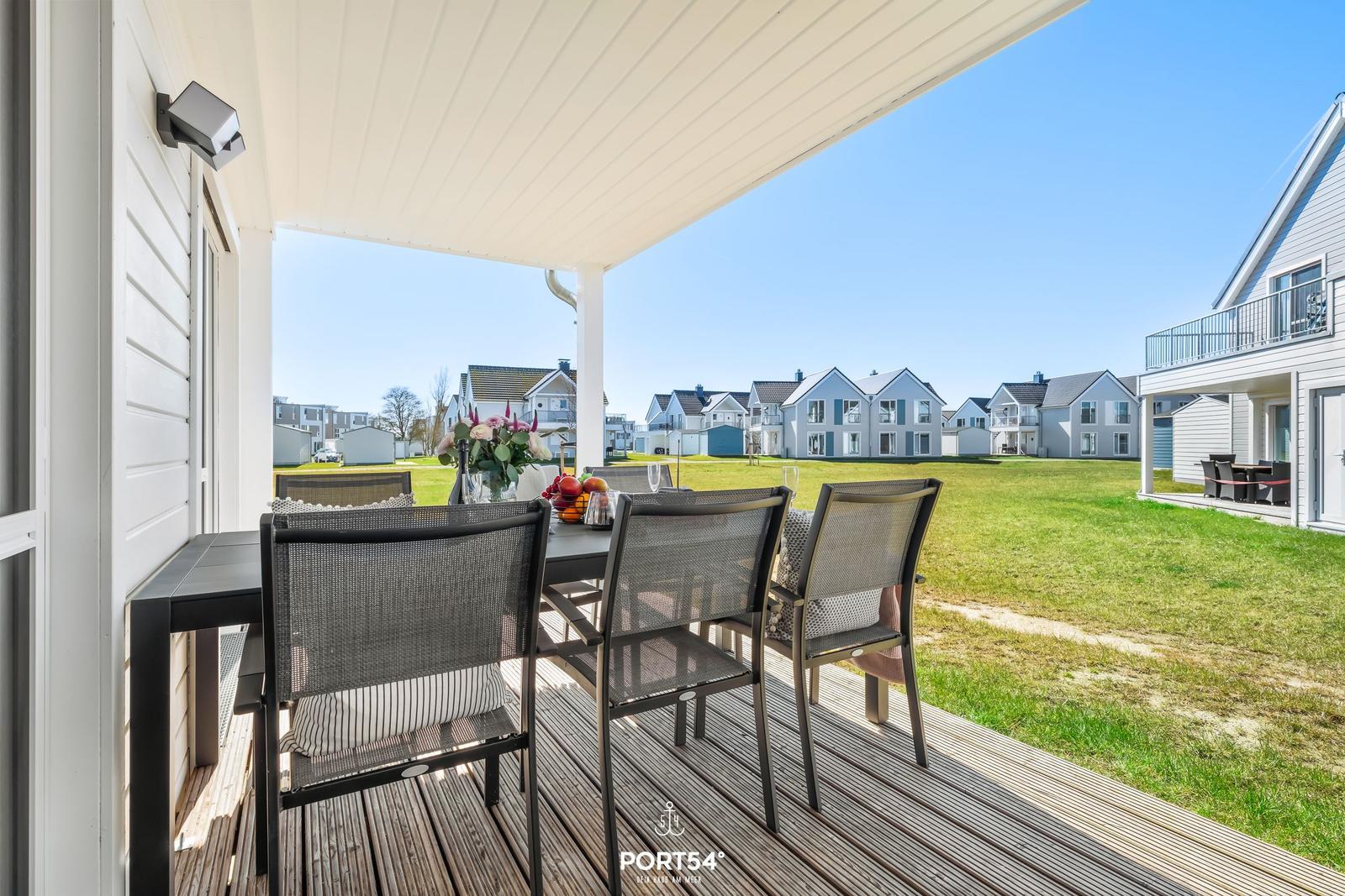 Terrasse mit Sitzgruppe und Blick auf grünen Rasen und Häuser