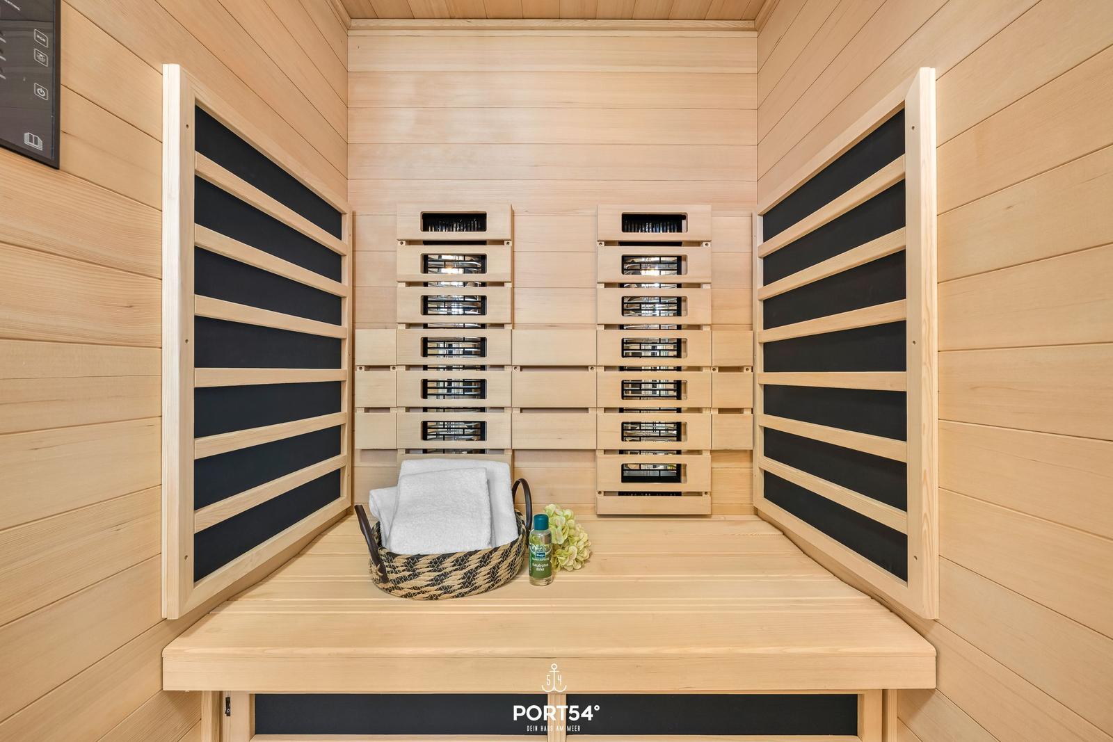 Sauna mit Holzwand, Sitzbank und Handtuchkorb.