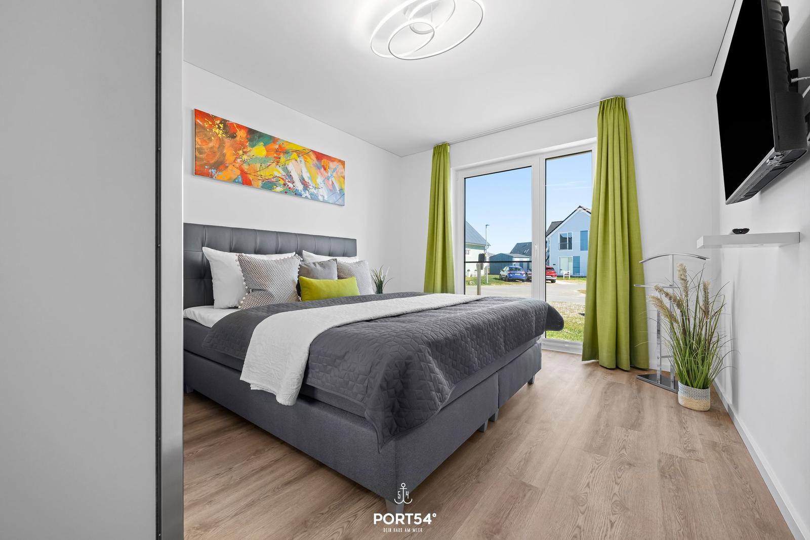 Schlafzimmer mit Bett, Fenster und Wandbild.