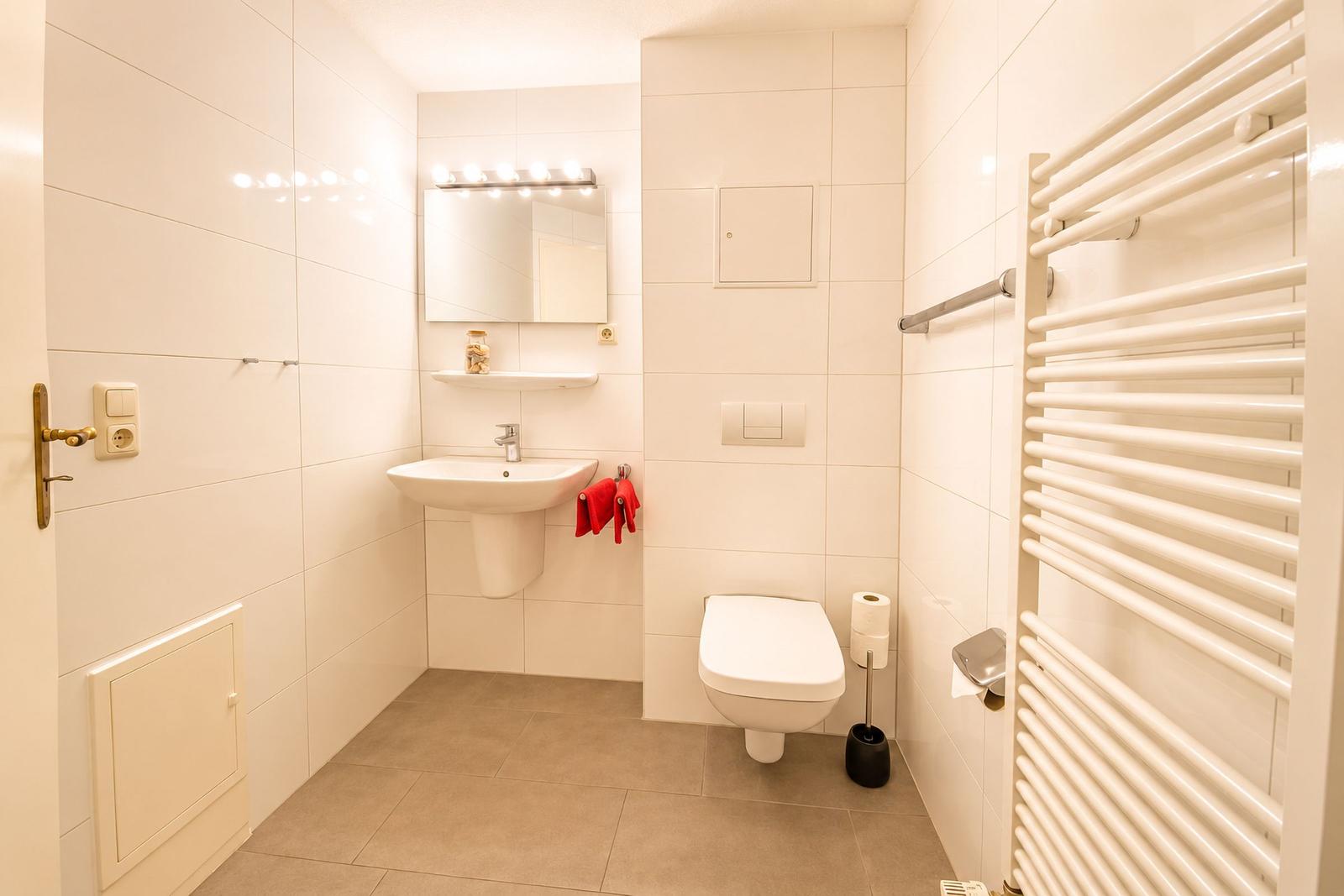 Badezimmer mit Waschbecken, Toilette und Heizkörper