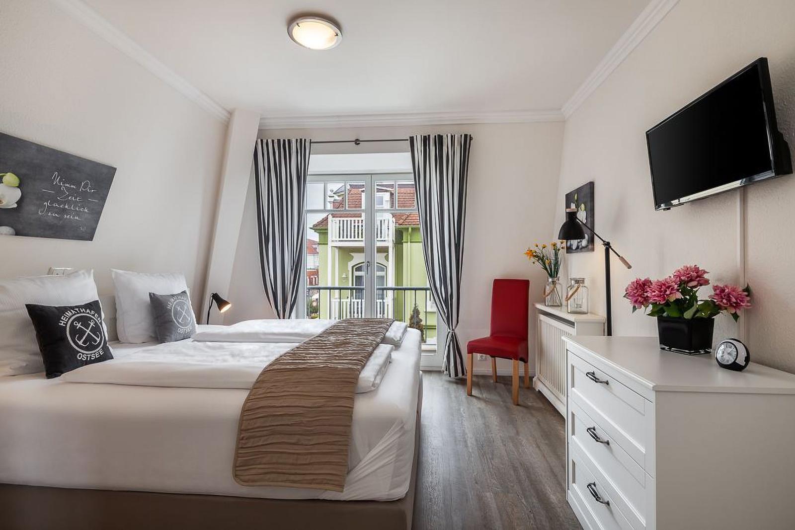 Schlafzimmer mit Bett, Fenster, Schrank und Fernseher.
