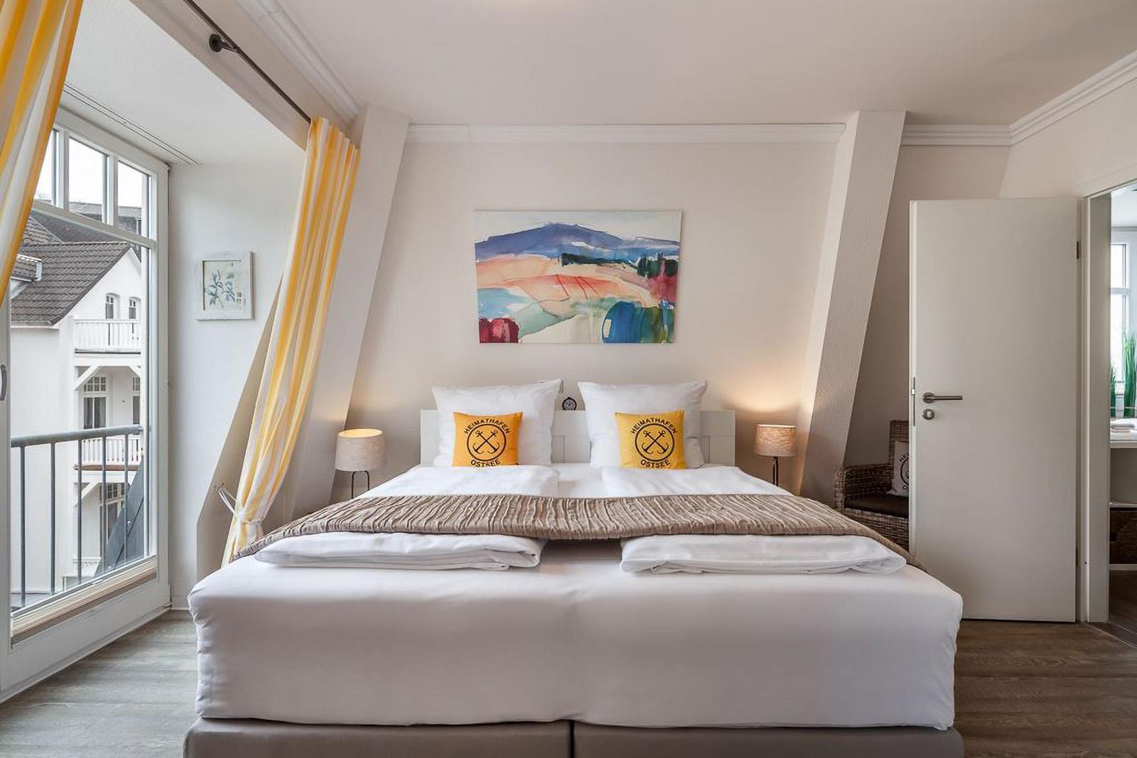 Schlafzimmer mit Doppelbett, Fenster und Wandbild.