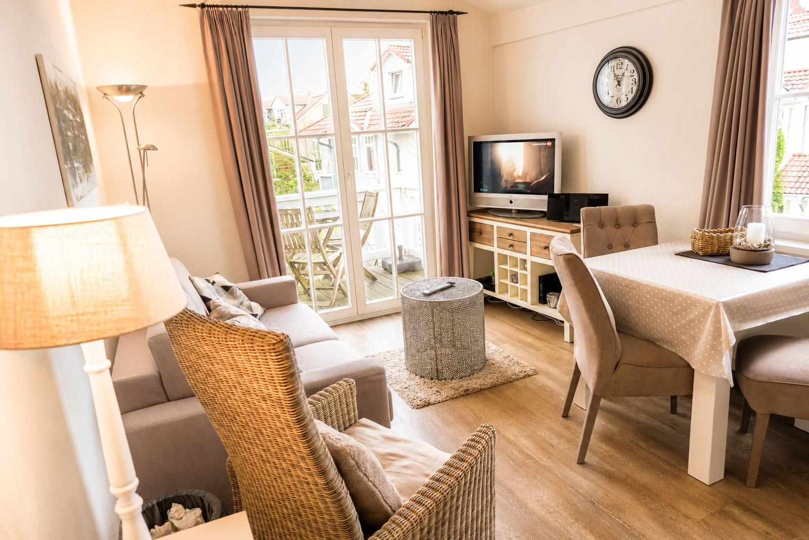Wohn- und Essbereich mit TV, Tisch, Stühlen und Blick auf Balkon.