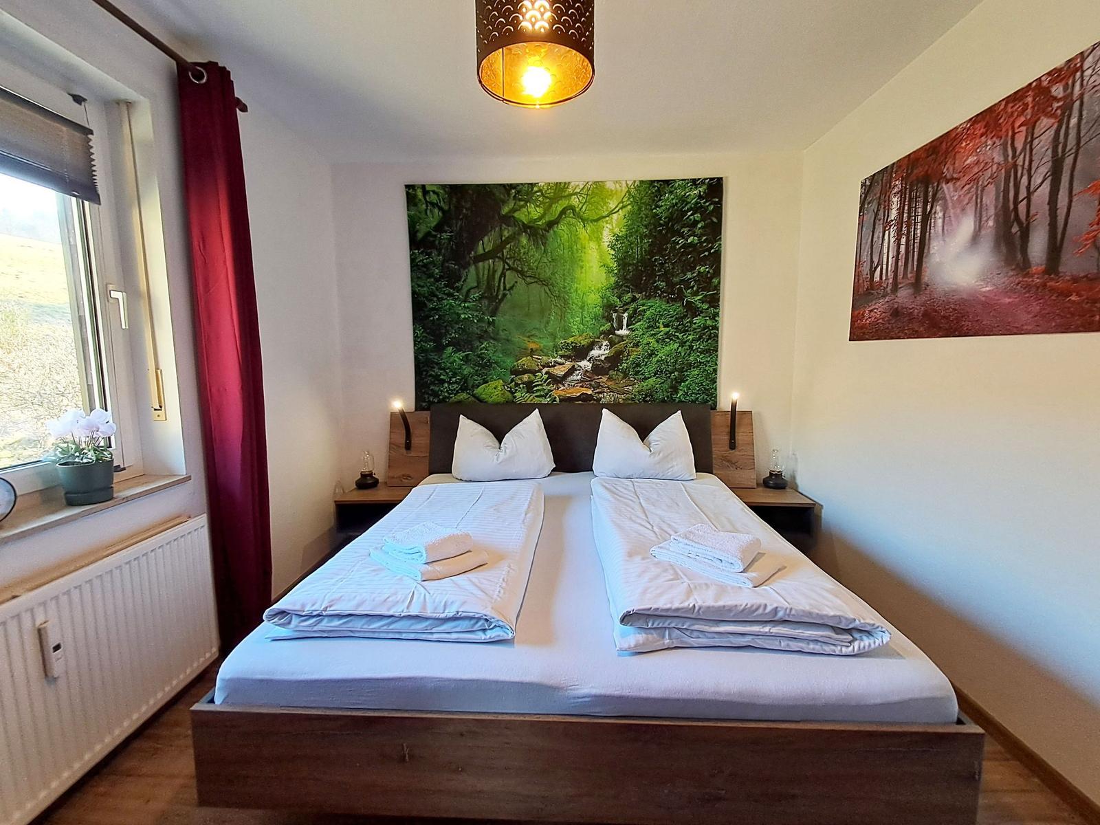 Schlafzimmer mit Doppelbett, Wandbild und Fenster mit Blick.