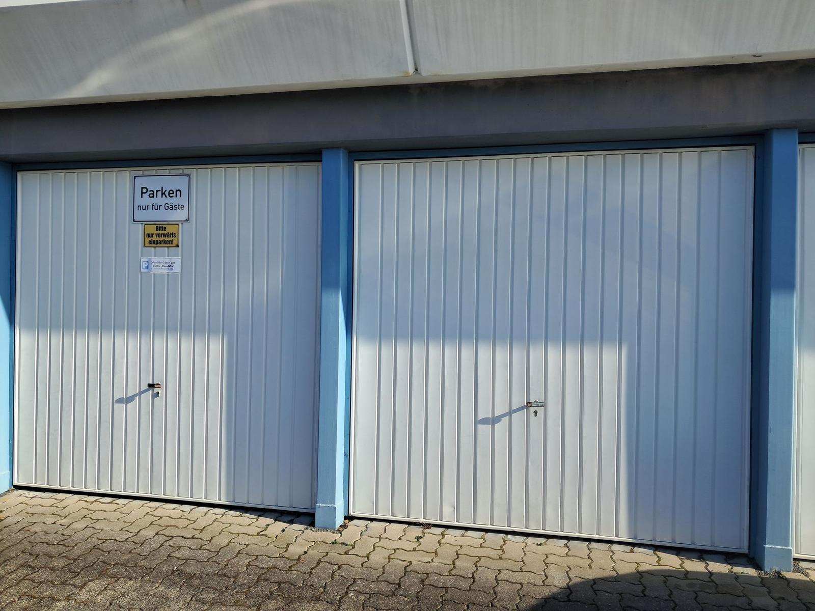 Zwei weiße Garagentore mit Schildern für Gäste