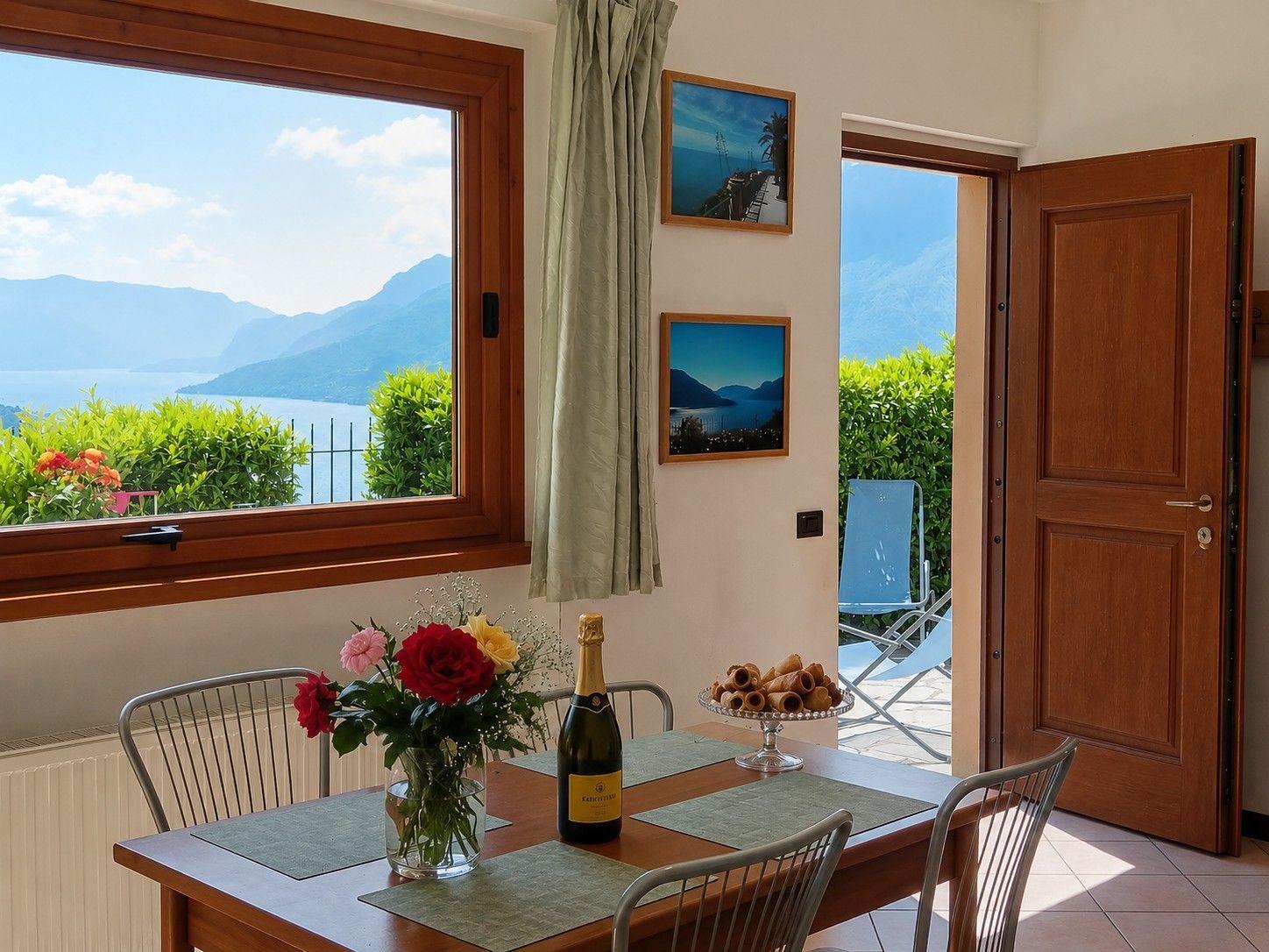 Esszimmer mit Tisch, Stühlen und Blick auf See und Berge.