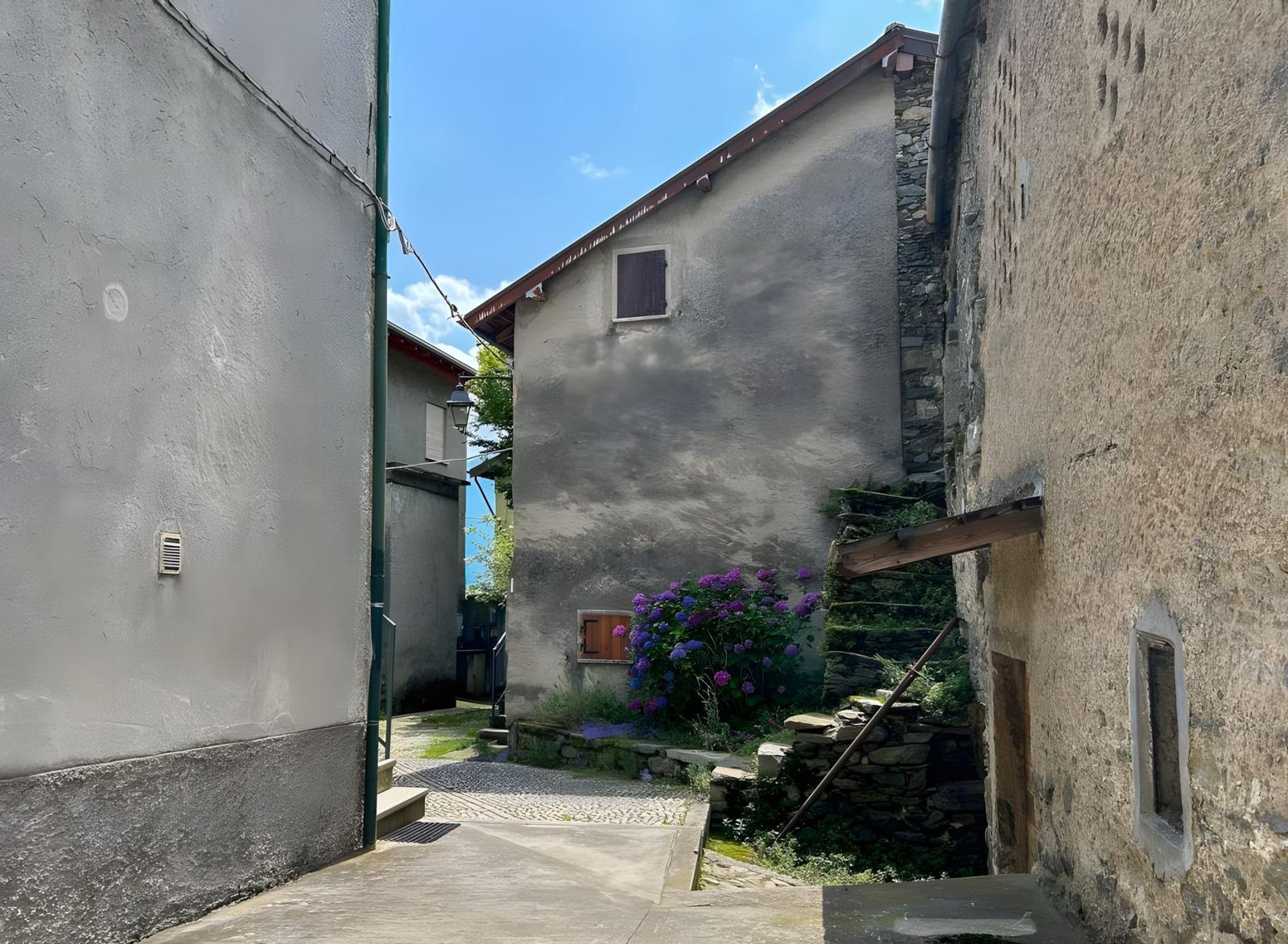 Enge Gasse zwischen alten Häusern mit Steinmauern und blühenden Hyazinthen.
