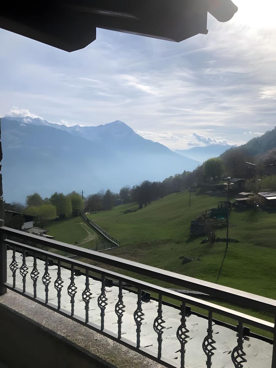 Balkon mit Blick auf grüne Hänge und schneebedeckte Berge.
