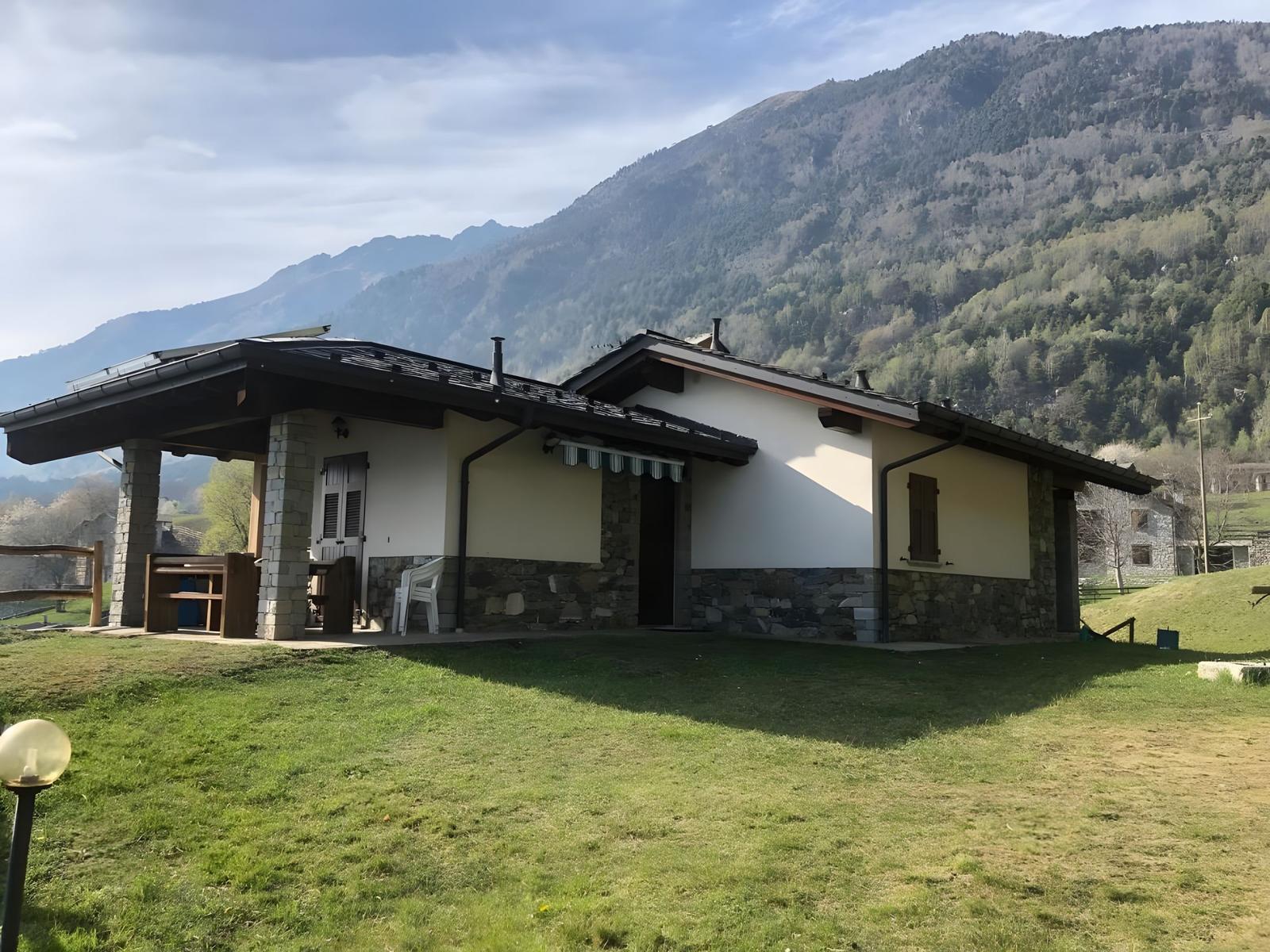 Haus mit Terrasse und Blick auf bewaldete Berge.