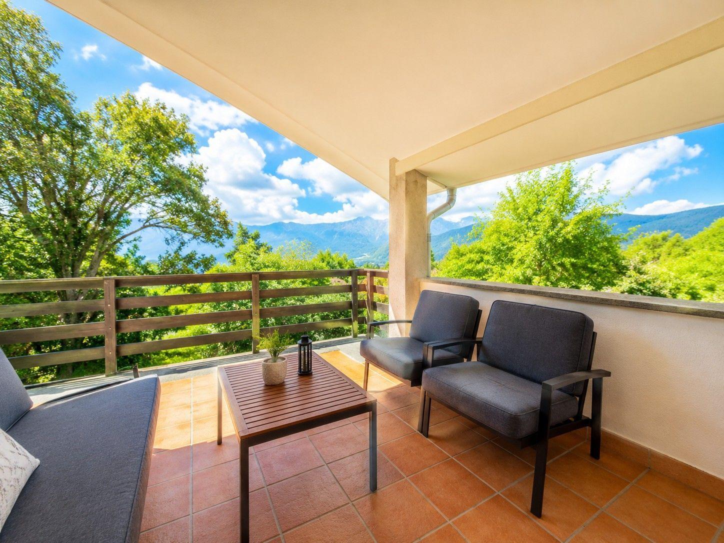 Terrasse mit Sitzgelegenheiten und Blick auf Berge und Bäume.
