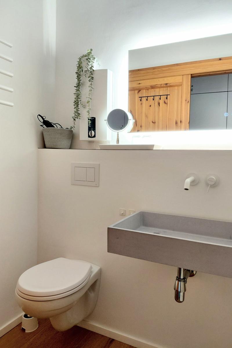 Badezimmer mit Toilette, Waschbecken und Spiegel