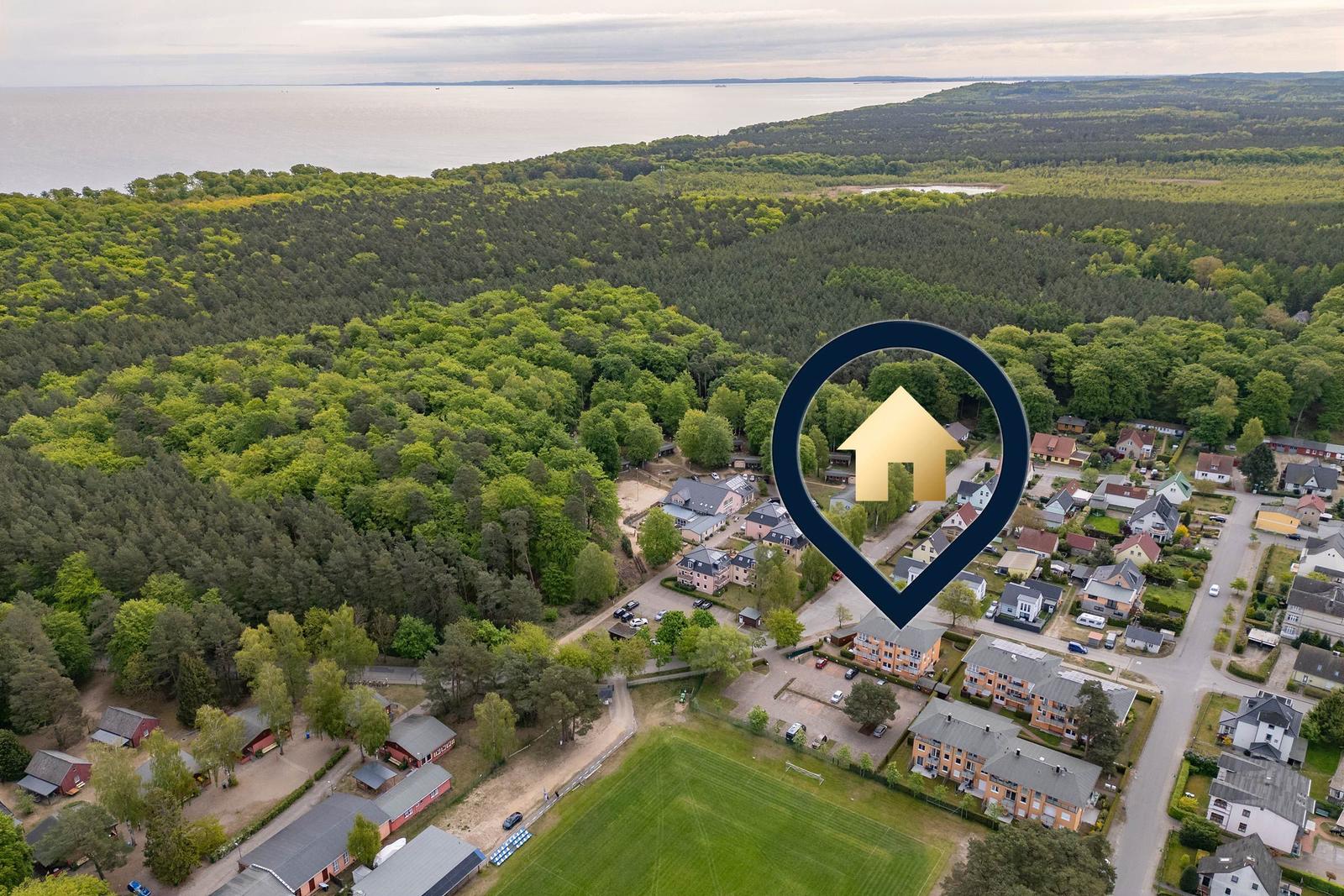 Aerial view of residential area with forest and sea in background