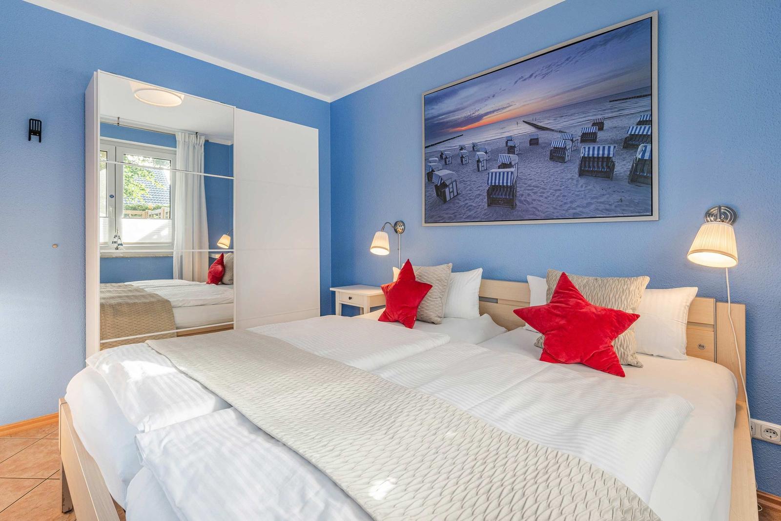 Bedroom with double bed, blue walls, and beach picture on the wall.