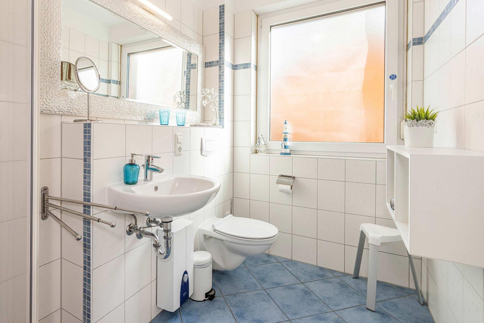 Bathroom with sink, toilet, and window. Tile floor and mirror cabinet.
